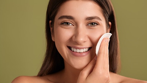 femme souriant et se démaquillant avec une lingette